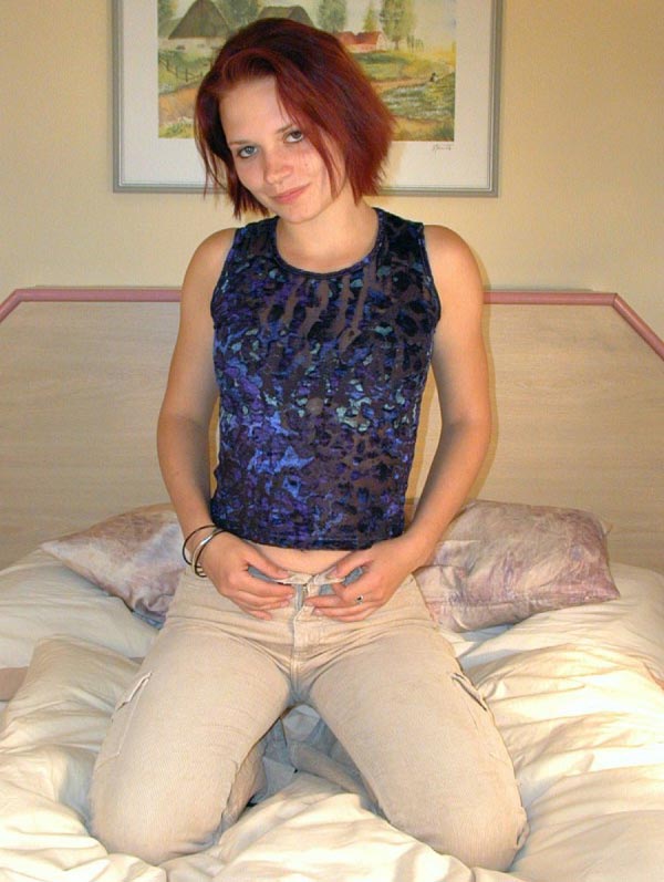 Hübsche junge Frau kniet auf dem Bett